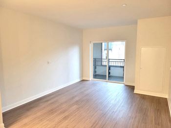 an empty living room with wood flooring and a balcony
